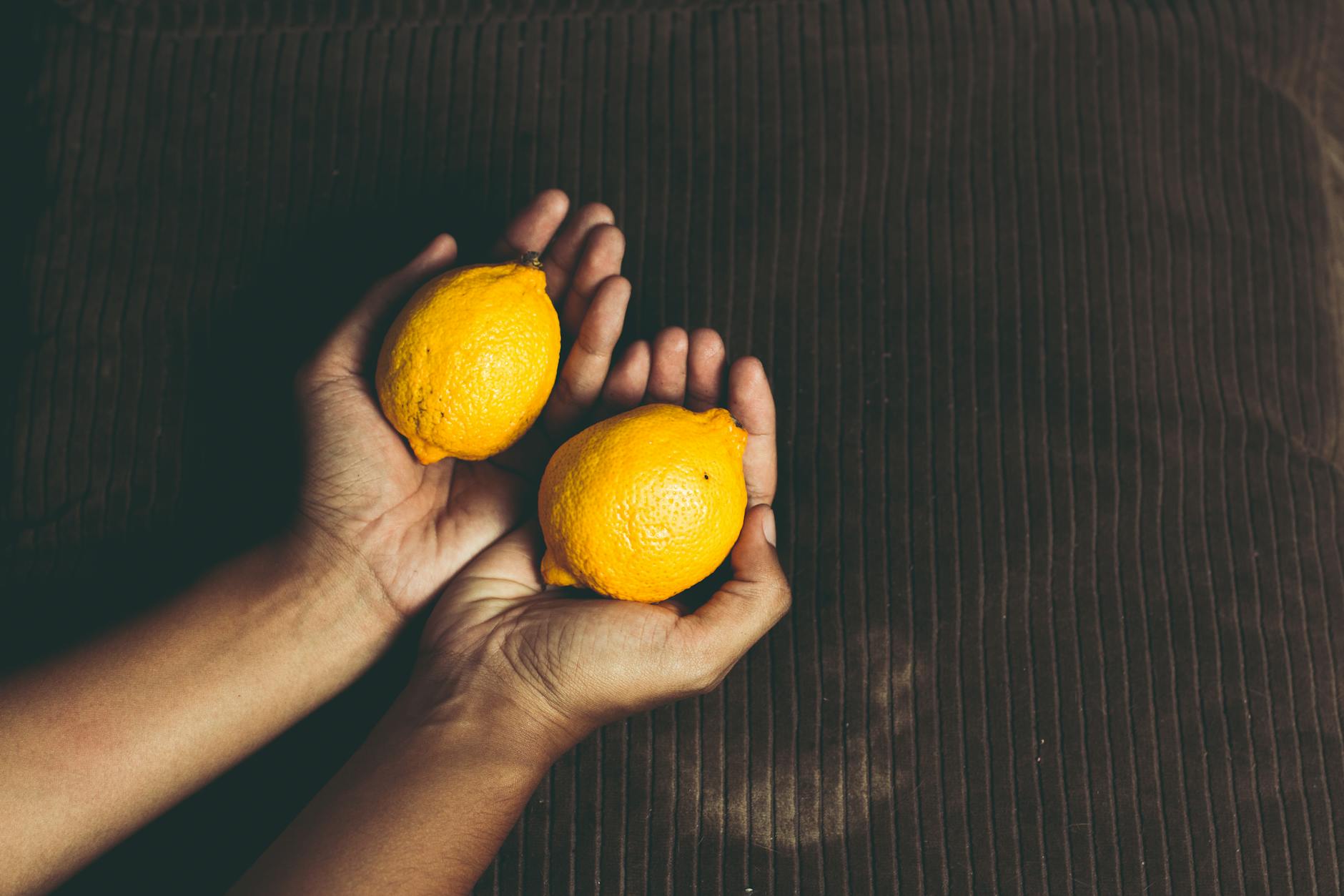 Close-up of hands holding a lemon vibrator against a knitted sweater