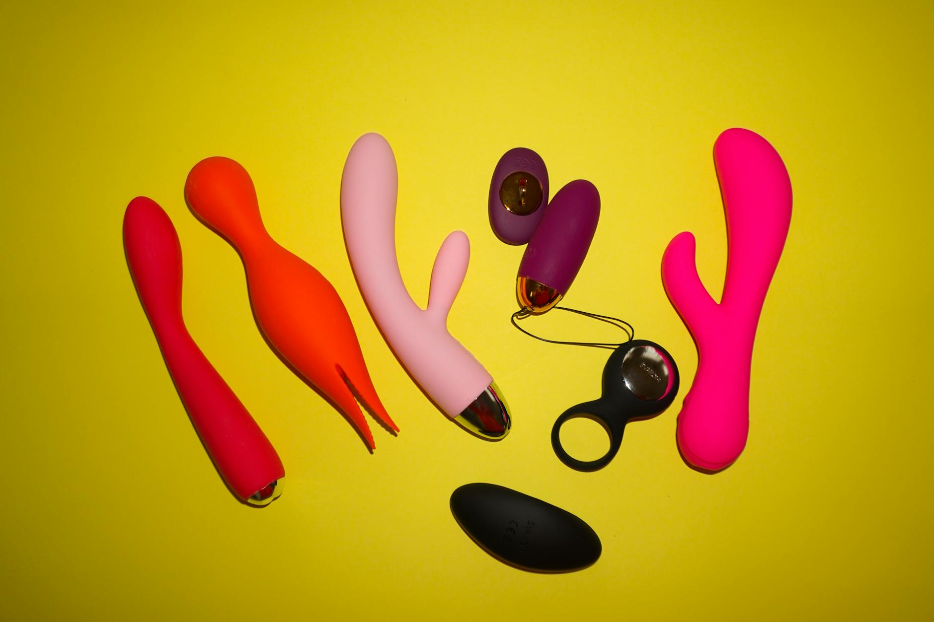 Colorful clitoral vibrators on a bright yellow background, including lemon-shaped designs